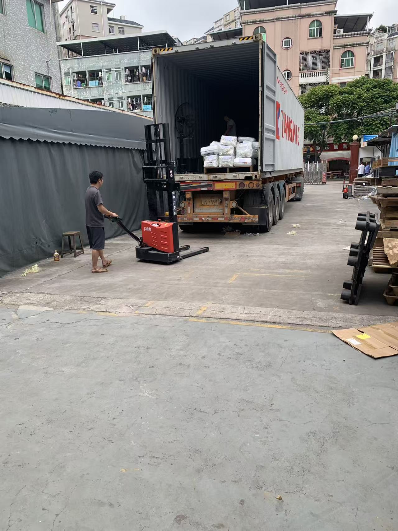 EP Equipment F3 electric pallet truck moving standardized export cargo into a Yang Ming container at Sealock shipping bay.