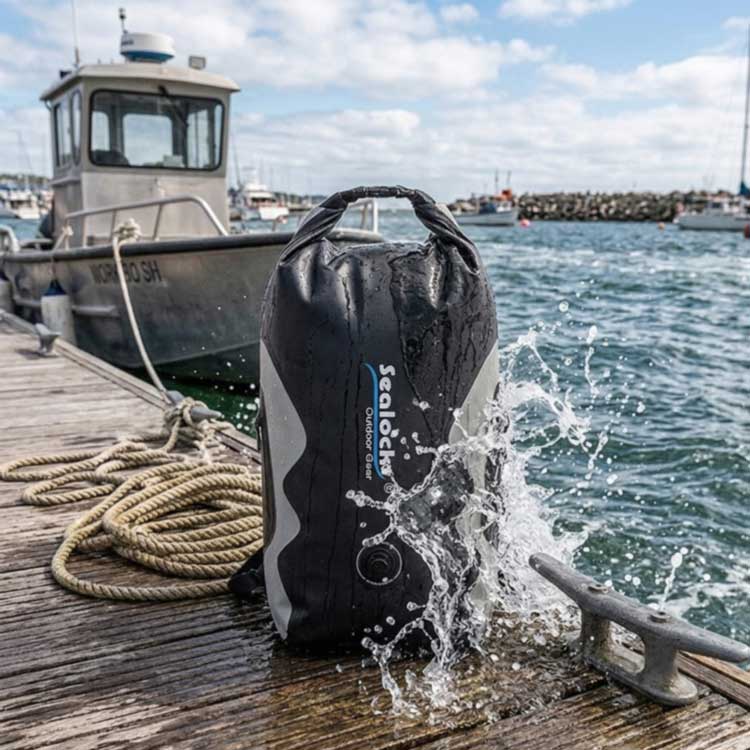 IPX8 waterproof travel bag at a boat dock with water splashing over the shell