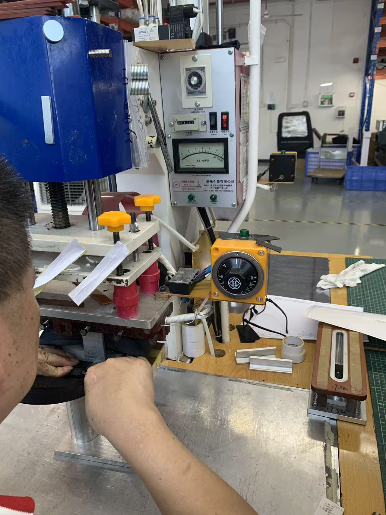 High-frequency welding press closed on a sling bag panel with the control panel visible